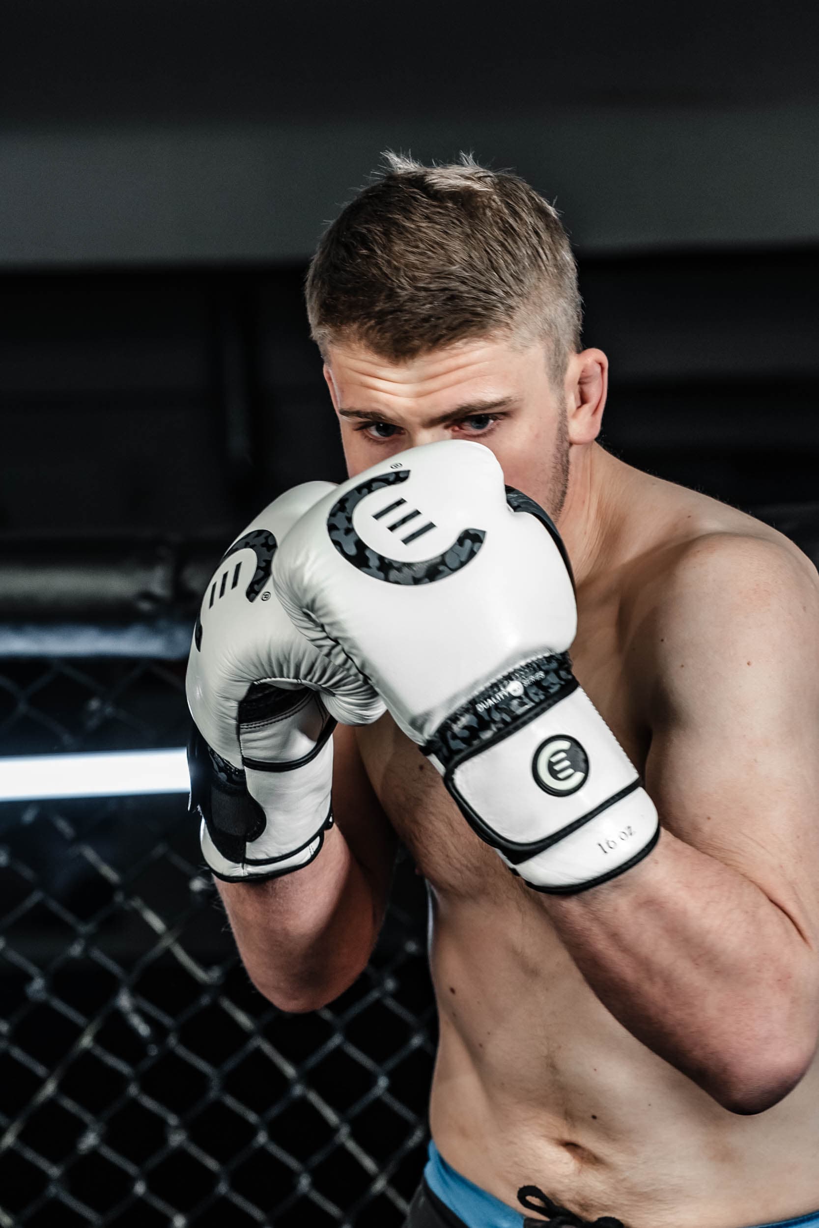 Evolve Combat — nærbilde guard med hvite hansker mot bur